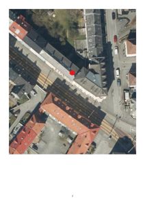 Flyfoto eller satellittbilde av et byområde med bygninger, veier og en markert rød prikk.