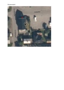 Bildet viser en situasjonsplan basert på et flyfoto eller satellittbilde. Det viser eiendommen med hus, gater (Torshavegata, Rakkeveien) og parkeringsplasser. Det er også lagt på et lokasjonspinn (pin) og et rødt rektangel som sannsynligvis markerer en planlagt inngang eller utvidelse.