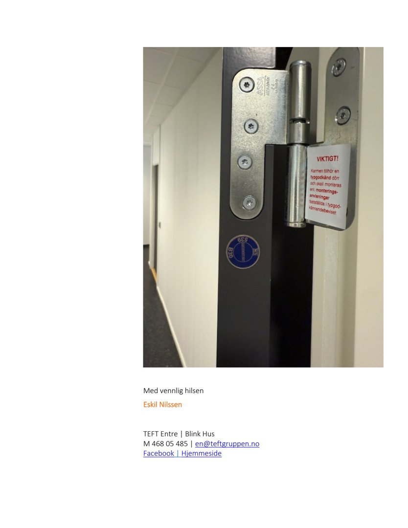 Fotografi av en dør med metalliske hengsler og et blått sikkerhetsmerke på dørrammen.