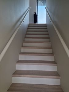 Fotografi av en trapp med tretrinn og hvite vegger.
