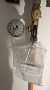 Fotografi av en vannmåler og ventil på en vegg.