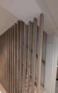 Fotografi av en innendørs trapp med en vertikal trepanelvegg.