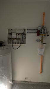 Fotografi av en gassinstallasjon med trykkmålere og en gassvarmer inne i et rom.