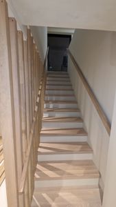 Fotografi av en trapp med tretrinn og trehåndtak.