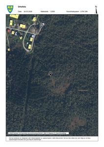 Ortofotobilde (flyfoto) av et område med skog og noen bygninger, med et markørpinn som indikerer en spesifikk lokasjon.
