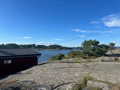 Fotografi av en rød bygning på en klipperommet med utsikt over vann og nabolag.