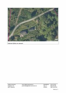 Historisk flyfoto som viser to bygninger og en vei i et grønt område.