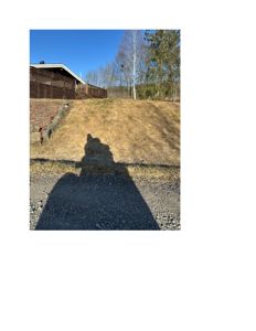 Fotografi av en bygning sett fra siden, med fokus på terrengforhold og skygger.