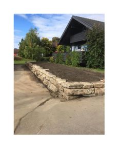 Fotografi av en ferdig eller nesten ferdig murt steinmur foran et hus.