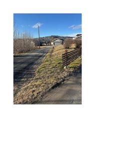 Fotografi av en vei, en hekk og en garasje i et boligområde.