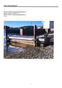 Fotografi av en kai eller brygge ved vannet med en bygning i bakgrunnen.