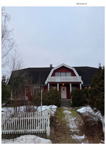 Fotografi av en rød villa med hvit balustrade og hvit gatehegn, sett fra foran.