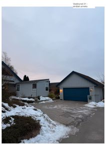 Fotografi av en bolig og garasjeanlegg med snø på bakken.