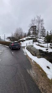 Fotografi av en bil som kjører på en vei i et snødekt landskap.