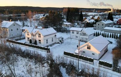 Fotografi av en boligbebyggelse i vinterlandskap med snødekte hus og trær.