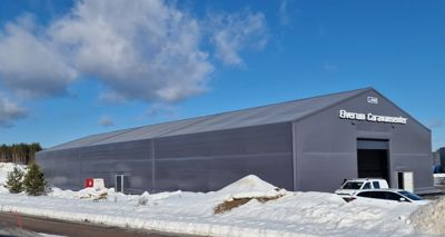 Fotografi av en stor, grå bygning (Everum Caravansenter) sett fra utsiden i vinterlandskap.