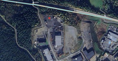 Flyfoto eller satellittbilde av et industriområde med veier, parkeringsplasser og bygninger.