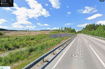 Fotografi av Fagermoevegen sett fra en bil, med en grusgrav eller byggeplass synlig i bakgrunnen.