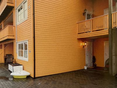 Fotografi av fasaden på en gul, trepanelt bygning med balkonger og vinduer.