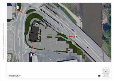 Satellittbilde (flyfoto) av et område med en bygning, parkeringsplasser og veier.