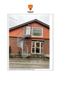 Fotografi av en bygning med spiraltrapp og fasade, inkludert kommunevåpen og beskrivende tekst.