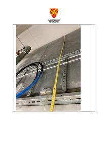 Fotografi av en metallkonstruksjon (sannsynligvis en takbjelke eller gulvplate) med en gul målebånd som er plassert langs den. Det er også synlig med kabler og en ventilasjonsrør.