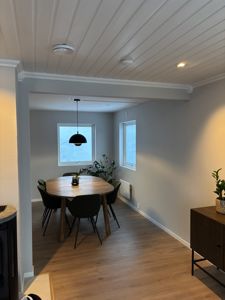 Fotografi av et innendørs rom (spisestue) med møbler, gulv, vegger og tak.