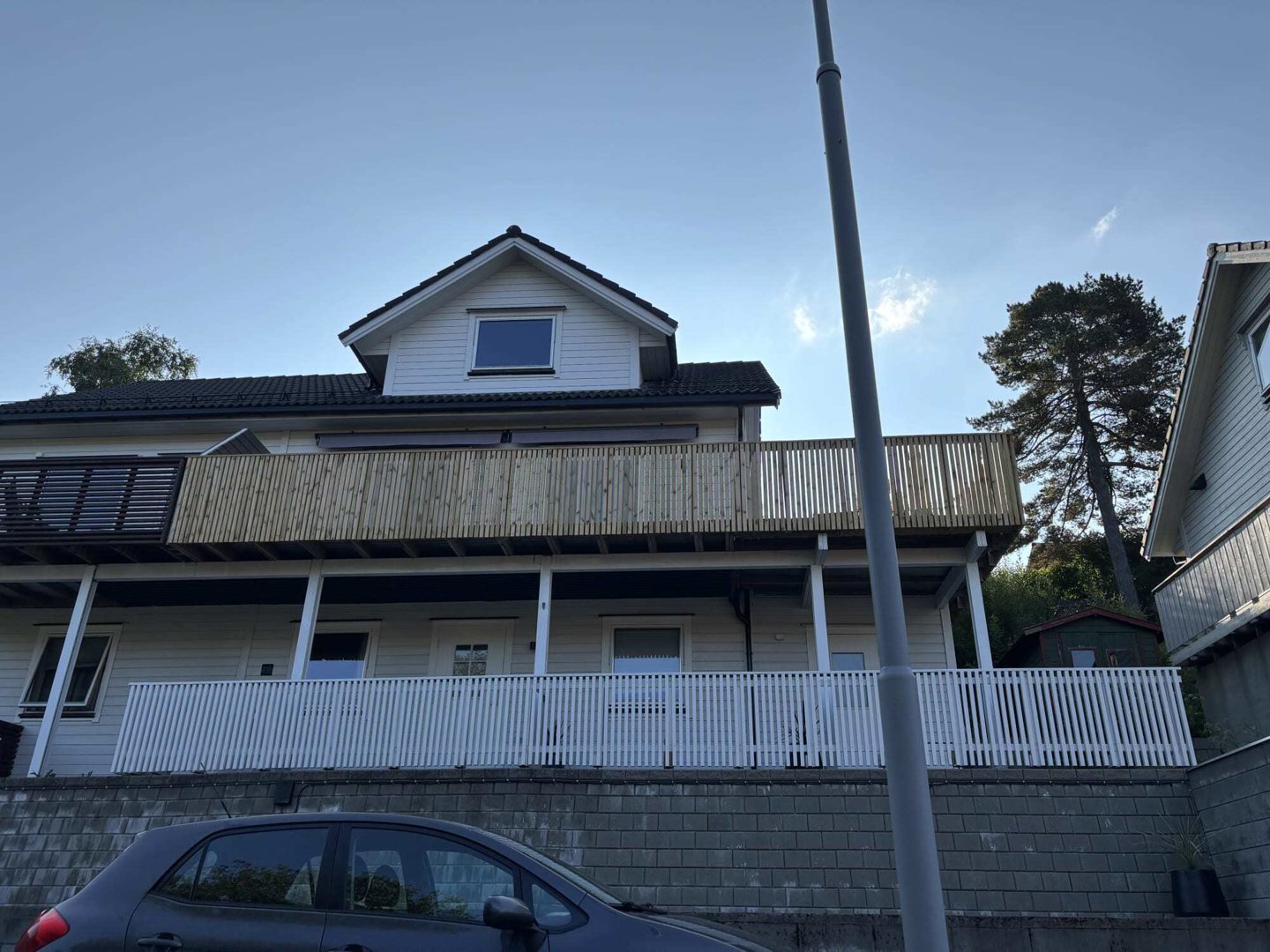 Fotografi av en eksisterende eller ferdigstilt villa sett fra gaten, som viser fasaden, balkonger og omgivelsene.