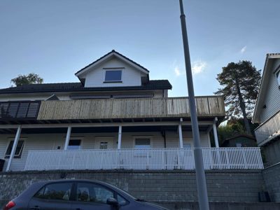 Fotografi av en eksisterende eller ferdigstilt villa sett fra gaten, som viser fasaden, balkonger og omgivelsene.