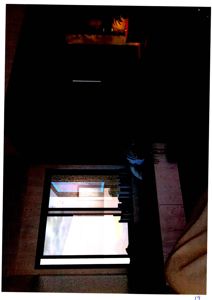 Fotografi av en mørk, innendørs trapp eller gang med et vindu som gir lys inn.