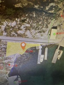 Satellittbilde eller kartutsnitt som viser et område med en markert tomt (gult) og en bygning (hvit).