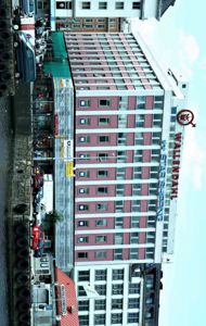 Fotografi av et fleretasjes bygg med 'WALLEND AHL' og 'STAR SHIPPING' skilt på fasaden, sett fra vannkant med bilparkering og andre bygninger i bakgrunnen.