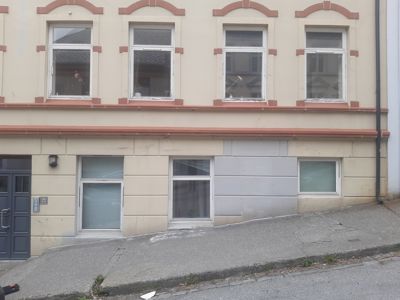 Fotografi av fasaden på en bygning med to etasjer, vinduer, dør og en fortau.