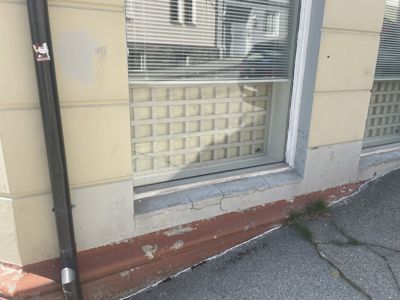 Fotografi av en fasade med vindu, nedløp og golvkant.