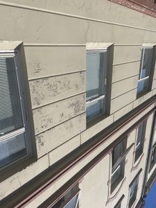 Fotografi av fasaden på en bygning, som viser vinduer, murverk og revne maling.