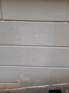 Fotografi av en gråmalt fasade på en bygning med håndskrevet tekst på veggen.