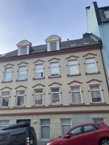 Fotografi av fasaden på en eksisterende bygning med flere vinduer og etasjer.