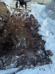 Fotografi av en utgravet grøft eller fundamenteringsgrøft på en byggeplass i snø.