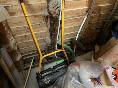 Fotografi av et rom med trepanelvegger, der det er plassert verktøy, rør og byggematerialer.