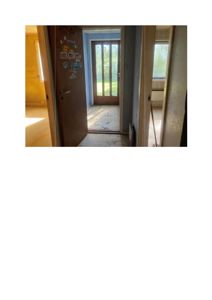 Fotografi av en inngangsparti i en bygning, med en åpen dør som leder ut til en hage.