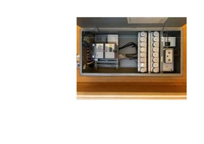 Fotografi av et åpent elektrisk sikringsskap med sikringer og måler.