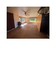 Fotografi av et tomt rom med panelvegger, gulv og takventilator.