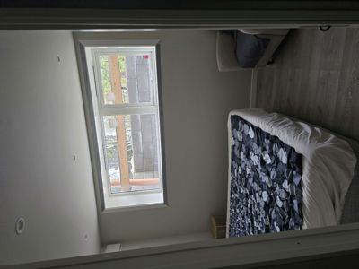 Fotografi av en innredet soverom med seng, stol og vindu.