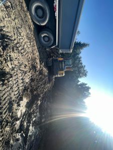 Fotografi av en byggeplass med en grøftmaskin og en lastebil på en mudderete tomt.