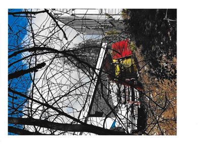 Fotografi av en bygning sett gjennom trær, med en blå himmel i bakgrunnen.