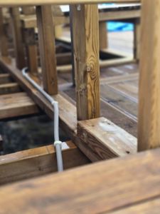 Fotografi av en konstruksjon i et bygg under oppføring, som viser trebjelker, stolper og en hvit rørledning.