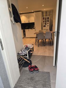 Fotografi av en inngangsparti og kjøkkenområde i en bolig, sett fra inngangsdøren innover.