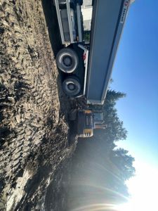 Fotografi av en byggeplass med en lastebil og en graver som jobber med å grave ut jorden.