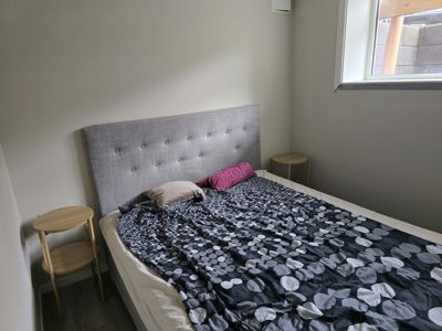 Fotografi av et innredet soverom med seng, nattbord og vindu.