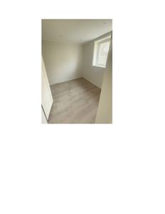 Fotografi av et tomt rom med gulv, vegger, tak og et vindu.